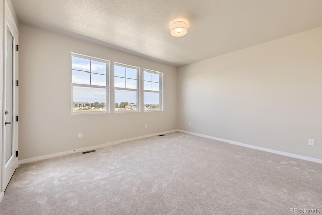 unfurnished room featuring baseboards, visible vents, a textured ceiling, and light colored carpet