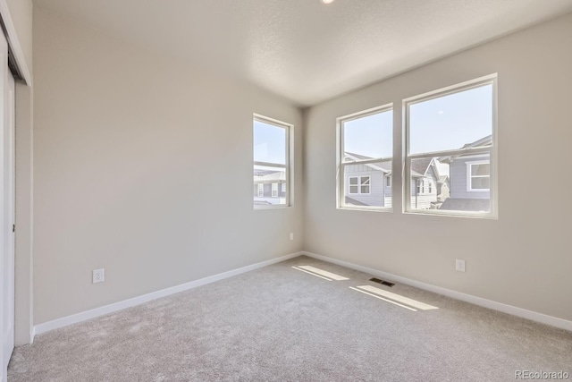 empty room featuring visible vents, baseboards, and carpet flooring