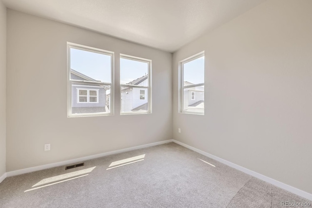 carpeted spare room featuring visible vents and baseboards