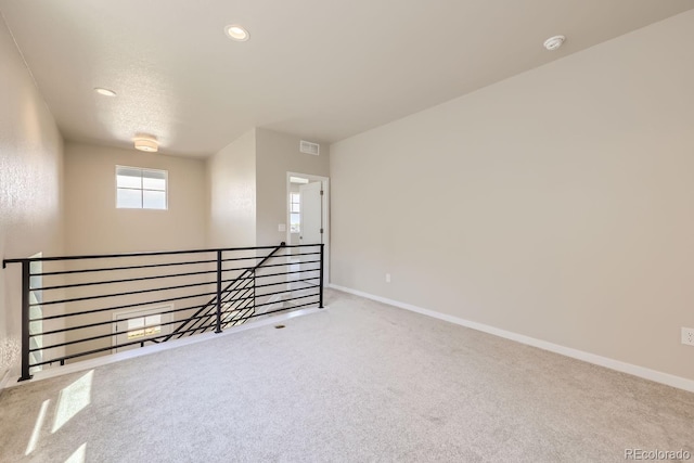 carpeted empty room with visible vents, baseboards, and recessed lighting