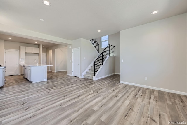 unfurnished living room with light wood-style floors, recessed lighting, and stairs