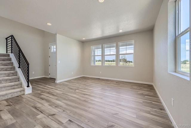 unfurnished living room featuring light wood-style floors, recessed lighting, stairway, and baseboards