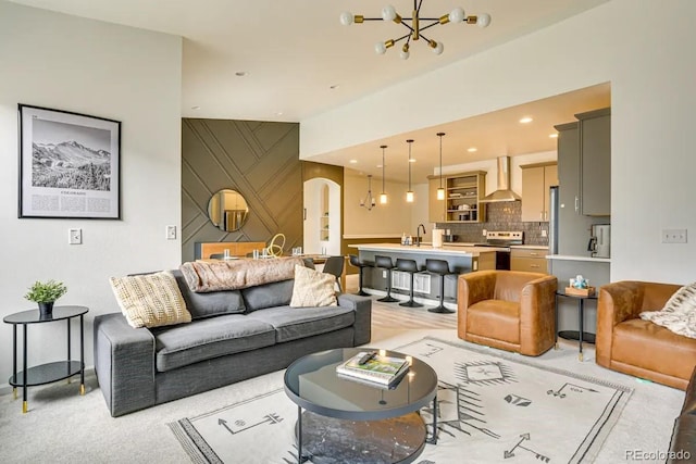 living area with arched walkways, an accent wall, a notable chandelier, and recessed lighting