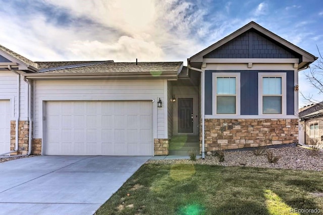 view of front of property with a garage, stone siding, concrete driveway, and a front yard