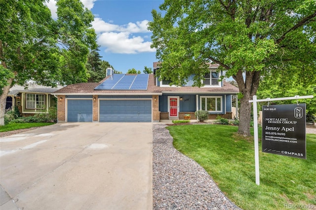 13701 Yank Way, Arvada, CO 80004 - view of front of home featuring brick siding, an attached garage, concrete driveway, a front lawn, and solar panels