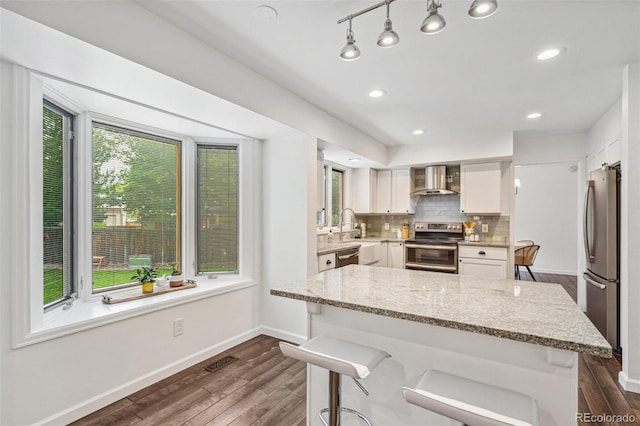 13701 Yank Way, Arvada, CO 80004 - kitchen with appliances with stainless steel finishes, wall chimney range hood, dark wood-type flooring, light stone countertops, and backsplash