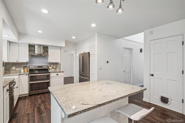 13701 Yank Way, Arvada, CO 80004 - kitchen with appliances with stainless steel finishes, wall chimney range hood, dark wood-style floors, decorative backsplash, and recessed lighting