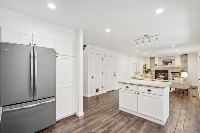 13701 Yank Way, Arvada, CO 80004 - kitchen featuring freestanding refrigerator, white cabinets, dark wood-style floors, light stone countertops, and a fireplace