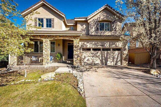 4968 Montvale Dr, Highlands Ranch, CO 80130 - view of front of property featuring stucco siding, driveway, a tile roof, a garage, and covered porch