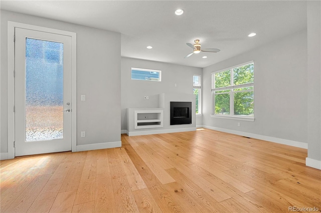 5988 N Boston St, Denver, CO 80238 - unfurnished living room featuring light wood-type flooring, a ceiling fan, a glass covered fireplace, recessed lighting, and built in shelves