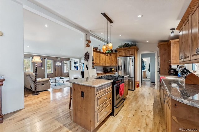 kitchen with appliances with stainless steel finishes, light wood-type flooring, vaulted ceiling, brown cabinets, and a kitchen island