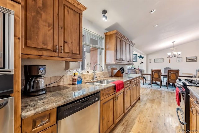 kitchen featuring stainless steel appliances, a sink, vaulted ceiling, light wood-style floors, and brown cabinetry