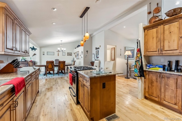 kitchen featuring gas stove, lofted ceiling, light wood-style flooring, a center island, and a chandelier