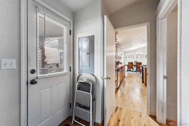 foyer with light wood-type flooring, lofted ceiling, a chandelier, and electric panel