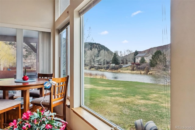 sunroom featuring a water and mountain view