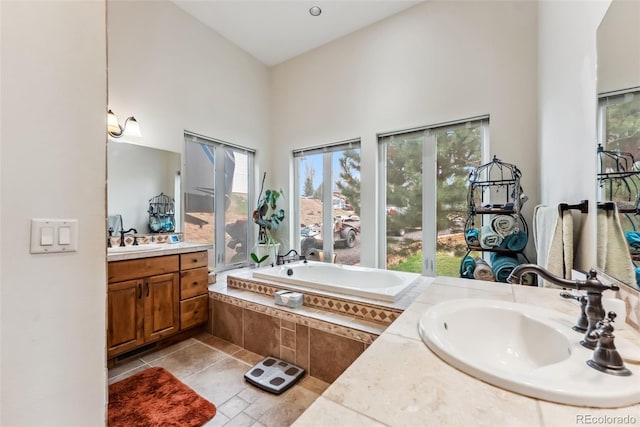 bathroom featuring healthy amount of natural light, a high ceiling, a garden tub, and two vanities