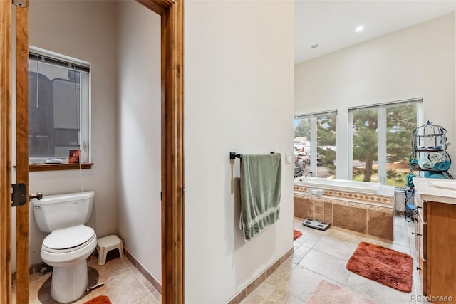 full bath with tile patterned flooring, a relaxing tiled tub, toilet, vanity, and recessed lighting