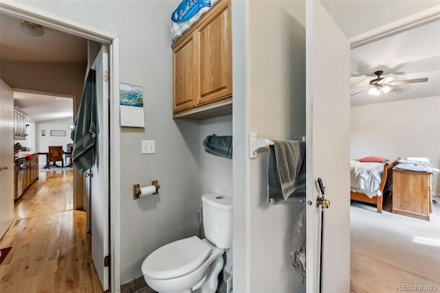 ensuite bathroom with toilet, ceiling fan, and wood finished floors