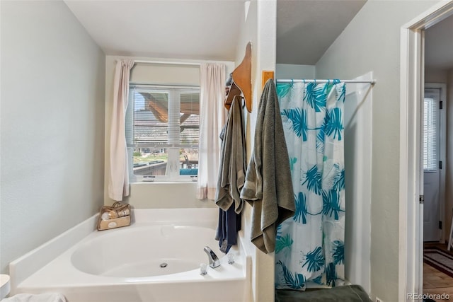 bathroom featuring a garden tub and curtained shower