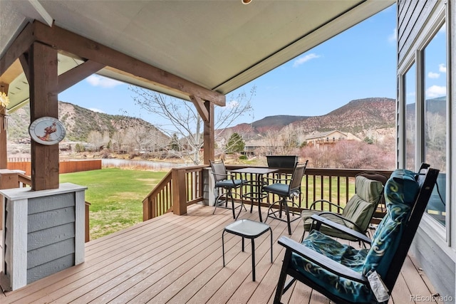wooden deck featuring a mountain view and a lawn
