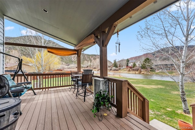 wooden deck featuring a water view and a yard