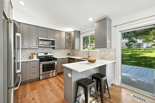 5193 S Flanders Ln, Centennial, CO 80015 - kitchen with gray cabinets, stainless steel appliances, a peninsula, light wood-style flooring, and vaulted ceiling