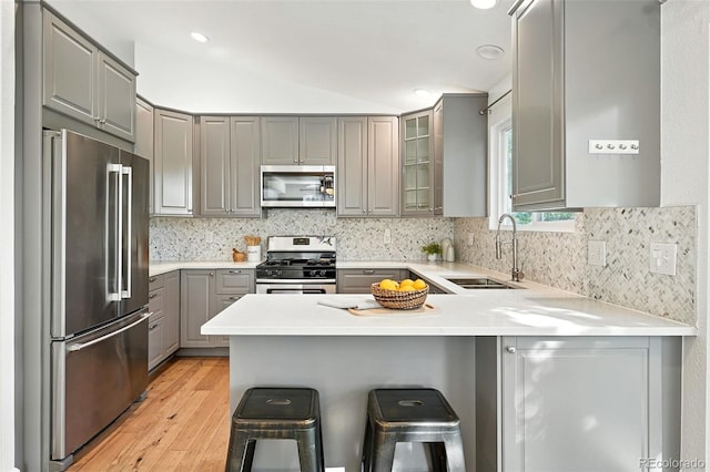 5193 S Flanders Ln, Centennial, CO 80015 - kitchen featuring stainless steel appliances, gray cabinets, a peninsula, light wood-style flooring, and a kitchen bar
