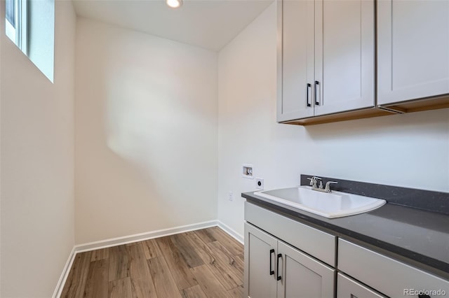 clothes washing area featuring sink, cabinets, washer hookup, hookup for an electric dryer, and light hardwood / wood-style flooring