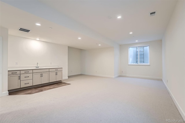 basement featuring light carpet and sink