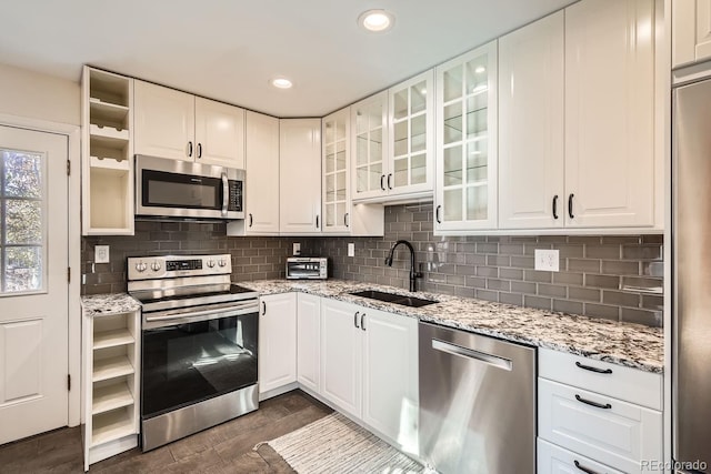 kitchen featuring sink, dark wood-type flooring, light stone counters, white cabinets, and appliances with stainless steel finishes