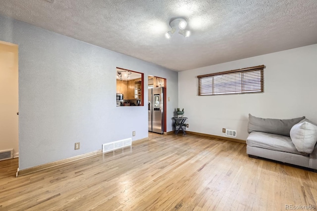 sitting room featuring wood finished floors, a textured ceiling, and baseboards