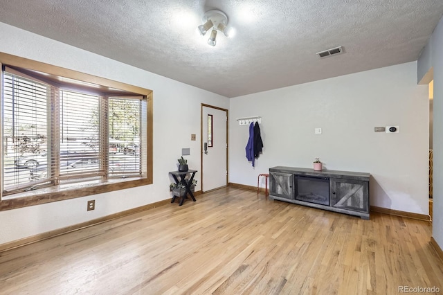 empty room with wood finished floors, a textured ceiling, and baseboards