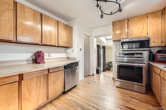 kitchen featuring stainless steel appliances, light countertops, light wood-style floors, and brown cabinets