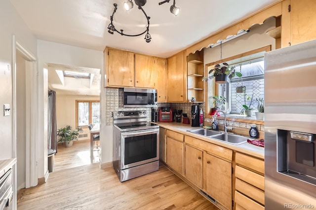 kitchen with appliances with stainless steel finishes, a sink, open shelves, a skylight, and tasteful backsplash