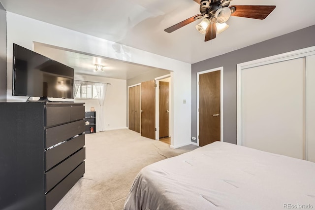 bedroom with carpet, baseboards, multiple closets, and ceiling fan