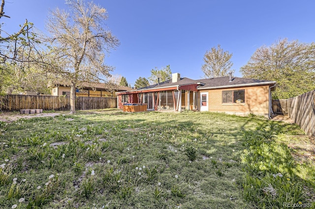 rear view of property with a sunroom, brick siding, and a chimney