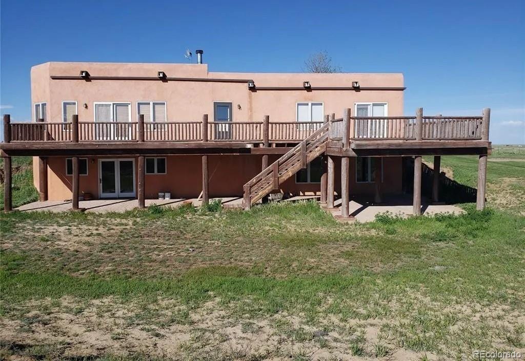 back of property with a wooden deck, a lawn, and a patio