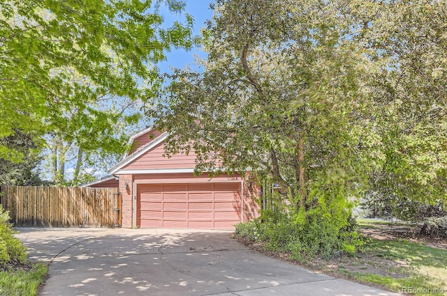garage featuring driveway and fence