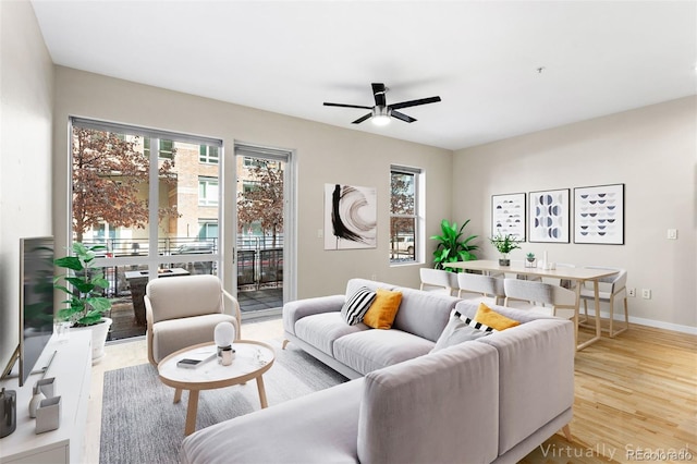 living area featuring light wood-style floors, ceiling fan, and baseboards