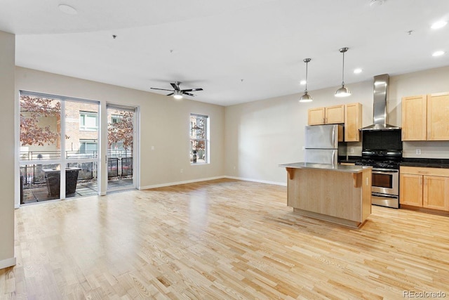 kitchen featuring open floor plan, appliances with stainless steel finishes, a center island, wall chimney exhaust hood, and decorative light fixtures