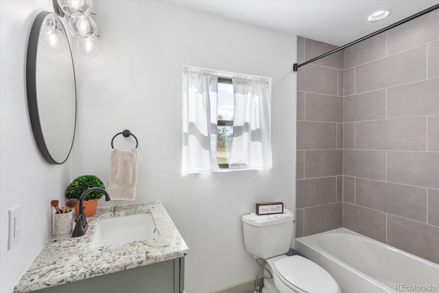 full bathroom featuring tiled shower / bath, vanity, and toilet