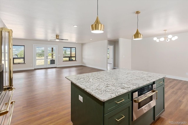 kitchen featuring pendant lighting, ceiling fan with notable chandelier, a center island, and dark wood-type flooring