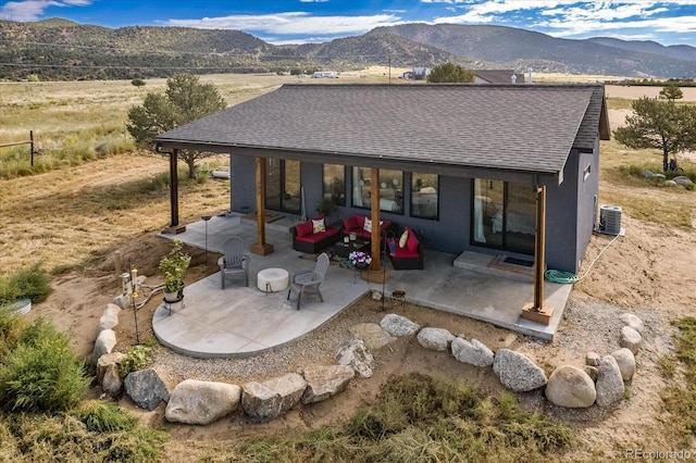 back of property featuring a patio area, a mountain view, an outdoor hangout area, and central AC