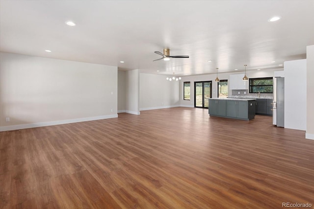 unfurnished living room with ceiling fan, dark wood-type flooring, and sink