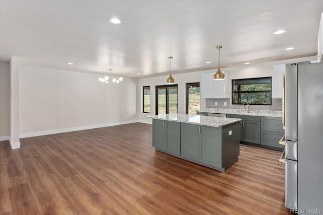 kitchen featuring pendant lighting, light stone countertops, appliances with stainless steel finishes, tasteful backsplash, and a kitchen island