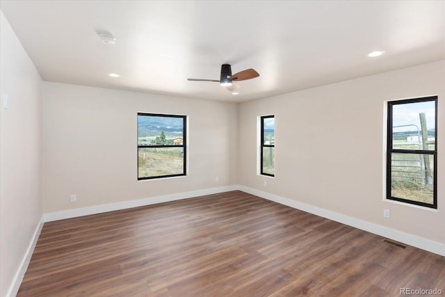 spare room with dark hardwood / wood-style flooring, plenty of natural light, and ceiling fan