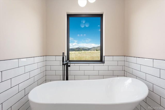 bathroom featuring a washtub and tile walls