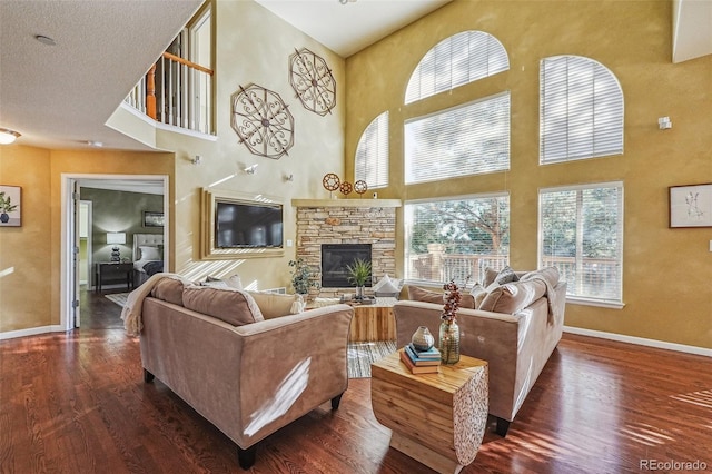 living room with dark hardwood / wood-style flooring, a towering ceiling, a fireplace, and a wealth of natural light