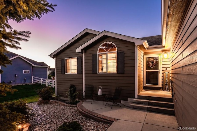 back house at dusk featuring a patio