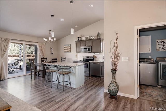 kitchen featuring pendant lighting, hardwood / wood-style floors, washer and clothes dryer, a center island, and stainless steel appliances